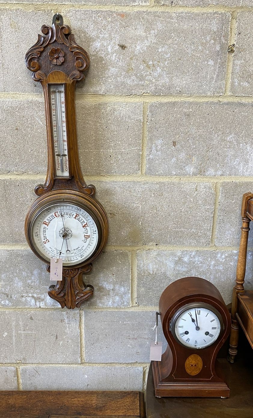 An Edwardian inlaid mahogany tear drop mantel clock, height 34cm and a carved oak aneroid wheel barometer, height 86cm *Please note the sale commences at 9am.
